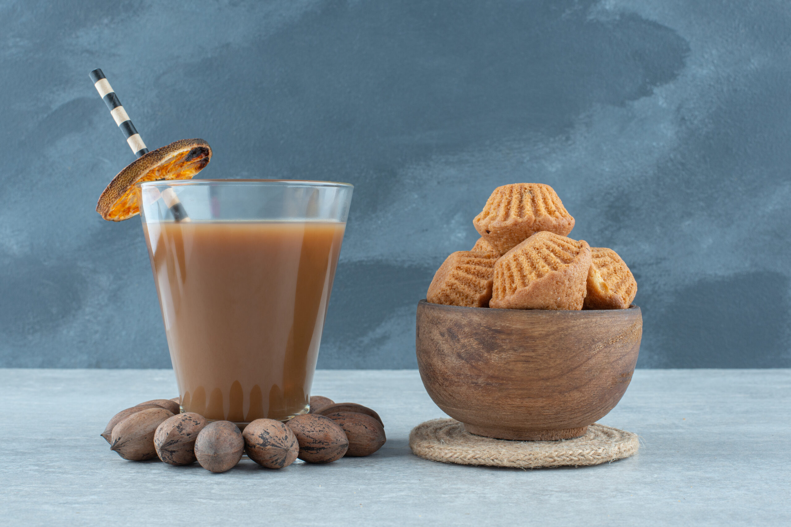 A glass of coffee with nuts and cookies