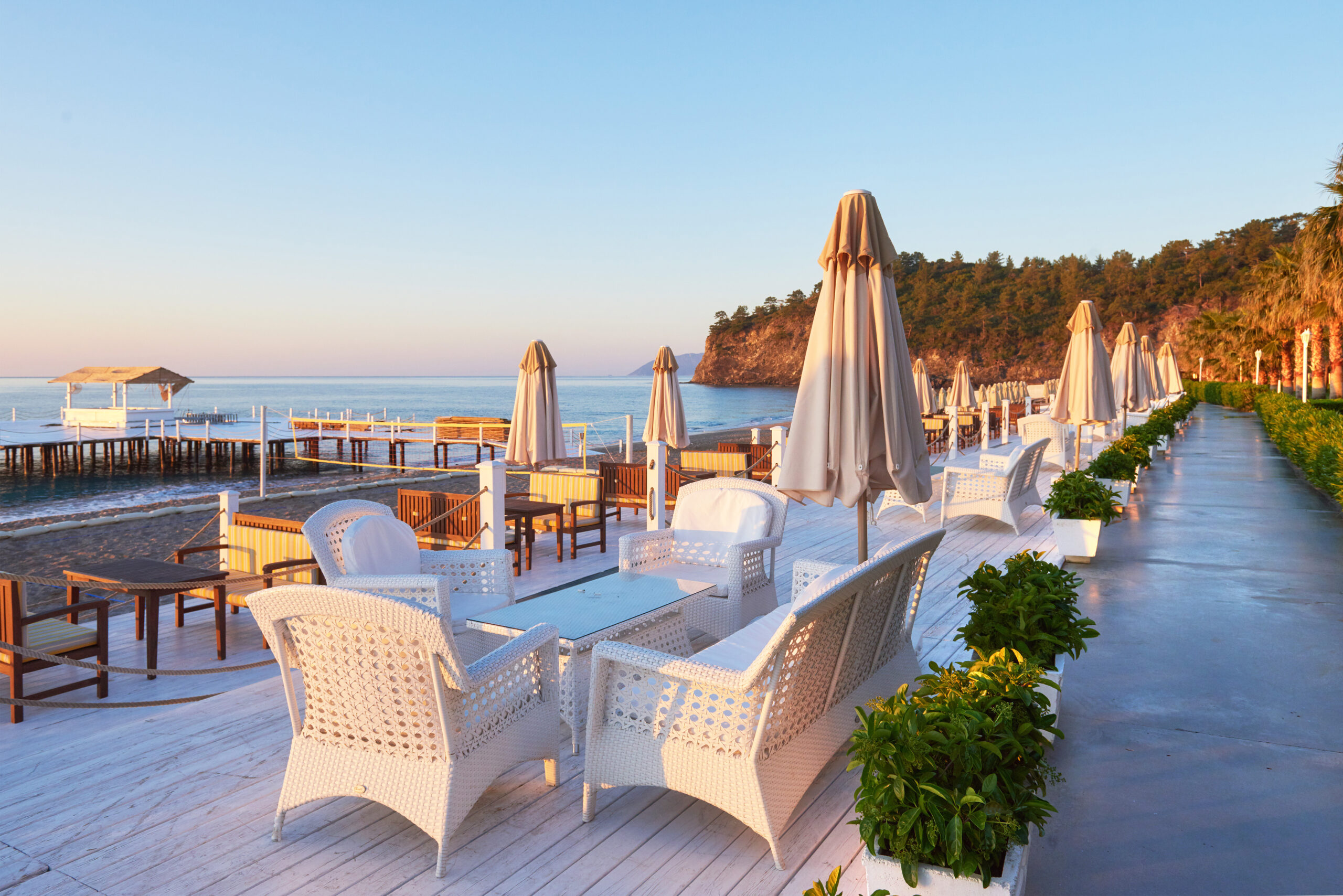 Scenic view of private sandy beach with sun beds and parasokamy the sea and mountains. Resort.
