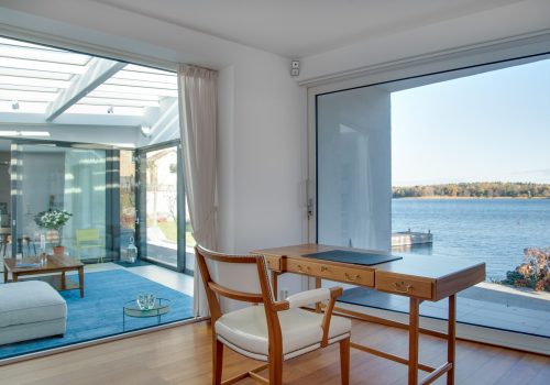 A luxury beach house with glass windows and the beautiful scenery of the sea in the background